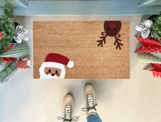 Handmade coir doormat with a Santa face and reindeer design. Made in the USA, available in three sizes, perfect for adding holiday cheer to your entryway. Diy Christmas Floor Mat, Christmas Mat Painting Ideas, Painted Door Mat Christmas, Christmas Outdoor Rug, Christmas Coir Doormat, Diy Painted Doormat Christmas, Diy Christmas Rug, Coir Doormat Diy Christmas, Christmas Mats Front Door