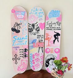 three snowboards with different designs on them sitting on a table next to a potted plant