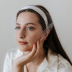 a woman wearing a veil and holding her hand to her face, looking at the camera