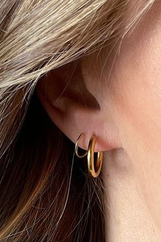 a close up of a person wearing gold earrings