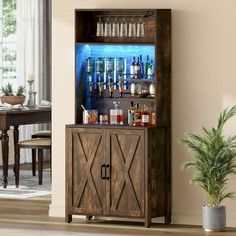 a wooden cabinet with liquor bottles on top and an illuminated bar in the middle, next to a potted plant