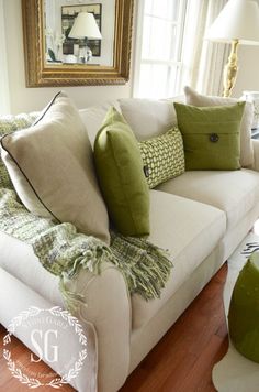 a white couch with green pillows on it