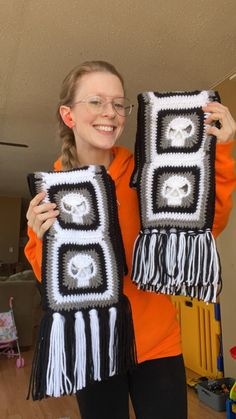 a woman holding two crocheted skulls and fringes