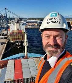 a man wearing a hard hat and safety vest standing in front of a large body of water