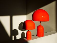 an orange lamp sitting on top of a white shelf next to a shadow cast wall