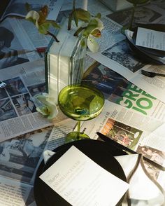 the table is covered with newspapers, magazines and glass vases filled with orchids