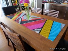 a wooden table topped with a vase filled with yellow and pink flowers on top of it