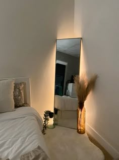 a white bed sitting next to a tall mirror on the wall in front of it