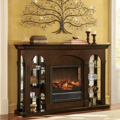 a living room with a fire place and a tree on the wall above it's mantle