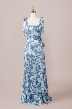 a blue and white floral print dress on a mannequin head stand in front of a pink background