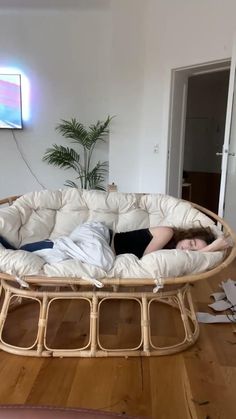 a woman laying on top of a bed in a living room next to a plant