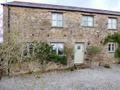 an old stone house with ivy growing on it's walls and windows, in the countryside