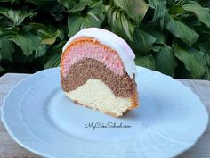 a slice of cake on a white plate with green leaves in the backgroud