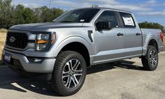 a silver truck is parked on the side of the road