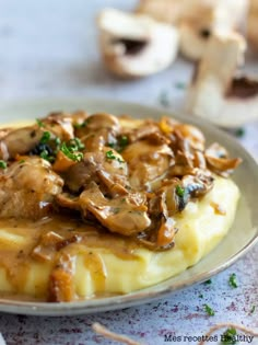 mashed potatoes topped with mushrooms and gravy on a plate