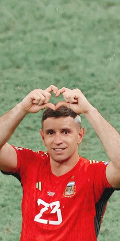 a soccer player is holding his hands up to the top of his head and making a heart shape