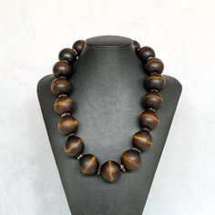 This chunky wood necklace was hand beaded using extra large 28mm round brown wooden beads, separated by complimentary brown and beige rondelles.  The necklace measures approximately 23 inches in length and is securely fastened with a silver clasp.  A fabulous unisex look for men or women!   Wood represents a sense of earthiness, spirituality, creativity, liberty, prosperity, health, and natural touch.  Perfect for meditation, prayer, yoga practices, and everyday wear!    Click on the link below Cheap Wooden Beads Round Necklace, Big Bead Necklace, Unisex Looks, Necklace Wood, Necklace Big, Necklace Mens, Wood Bead Necklace, Wood Necklace, Necklace Boho