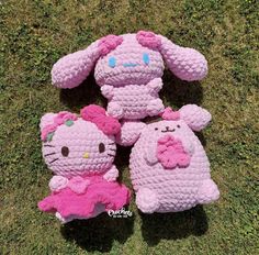 three crocheted hello kitty toys laying on the grass