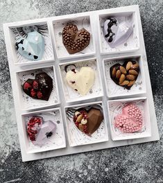 twelve heart shaped chocolates in a white box on a gray surface with silver decorations