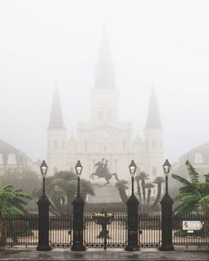 a person riding a horse in front of a large building on a foggy day