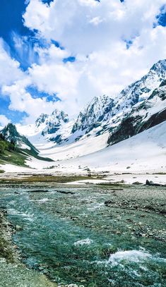 there is snow on the mountains and water in the river below it that runs through the valley