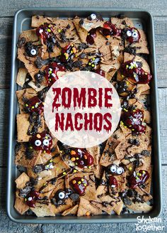 a tray filled with halloween nachos on top of a wooden table next to a sign that says zombie nachos