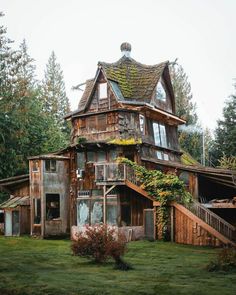 an old wooden house with ivy growing on it's roof and stairs leading up to the second floor