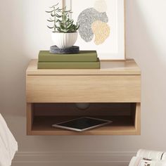 a phone is sitting on top of a nightstand next to a potted plant and books