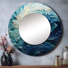 a round mirror sitting on top of a wooden table next to a vase with flowers