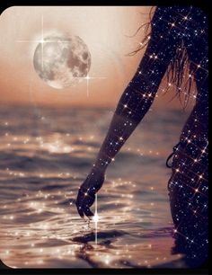 a woman is standing in the water with her hand out towards the moon and stars