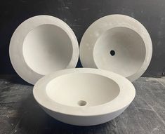 three white bowls sitting next to each other on top of a wooden table in front of a gray wall