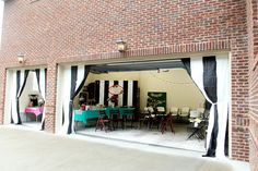 an open garage door with black and white striped curtains on the outside, showing tables and chairs