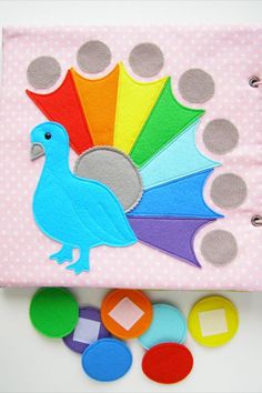 a colorful bird is on top of a pink fabric book with circles and dots around it