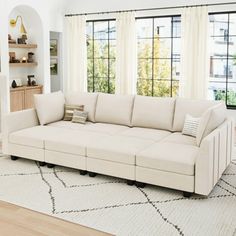 a living room filled with furniture and a fire place in front of two windows on top of a white rug