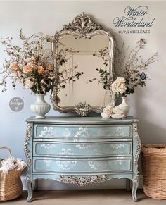 a blue dresser with flowers and a mirror on top