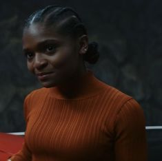 a woman in an orange sweater looking at the camera