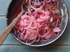 onions being cooked in a pan with a wooden spoon