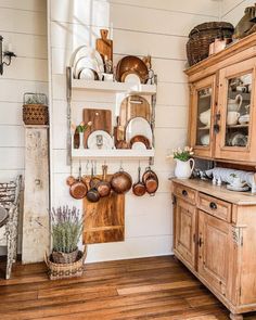 an old fashioned kitchen with wooden cabinets and dishes on the shelves, along with pots and pans