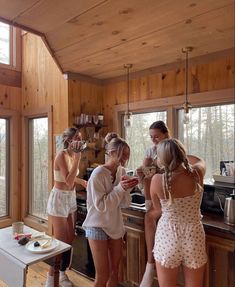 three women are standing in the kitchen and one is looking at something on the counter