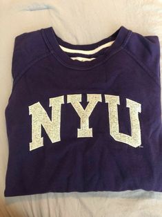 a purple shirt with the word nyu written in white on it's chest