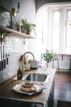 a wooden counter top in a kitchen next to a sink and oven with utensils on it