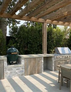 an outdoor kitchen with grill, table and chairs