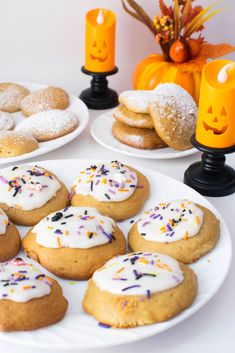 a white plate topped with cookies covered in frosting and sprinkles next to candles