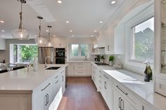 a large kitchen with white cabinets and wood floors