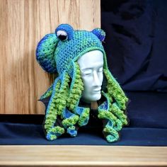 a crocheted hat with an octopus on it's head sits next to a mannequin