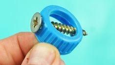 a person holding a small blue object with screws in it's center and thumb