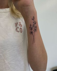 a woman's arm with a flower tattoo on the left side of her right arm