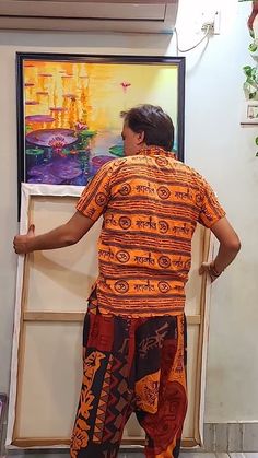 a man standing in front of a painting with his back turned to the camera and looking at it