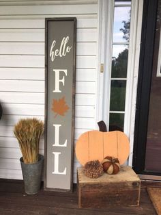 a wooden sign that says hello fall next to some pumpkins