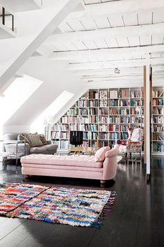 a living room with lots of bookshelves and a pink couch in the middle